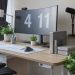 Ett välorganiserat skrivbord med en stor välvd datorskärm och gröna växter.